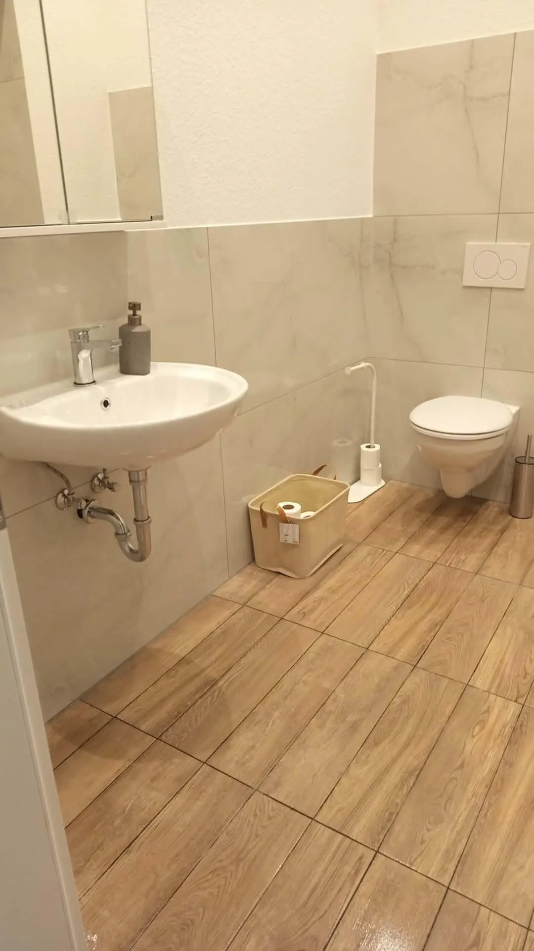 Gereinigtes Bad mit Waschbecken, WC und Fliesen in Holzoptik